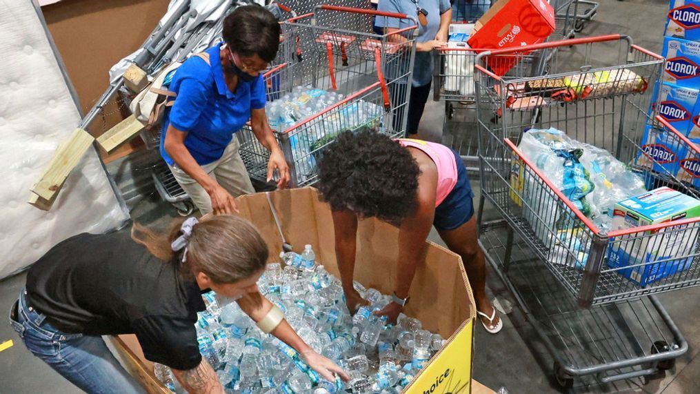 Shoppers at the Costco store in Altamonte Springs, Fla. grab bottles of water from the last pallet in stock on Monday, Sept. 26, 2022, as Central Floridians prepare for the impact of Hurricane Ian. (Joe Burbank/Orlando Sentinel via AP)