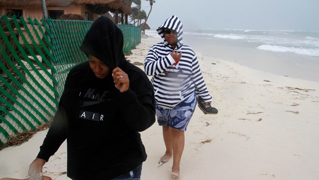 Tourists walk on the beach as the tail end of Hurricane Zeta makes landfall in Playa del Carmen, Mexico, early Tuesday, Oct. 27, 2020. Zeta is leaving Mexico’s Yucatan Peninsula on a path that could hit New Orleans Wednesday night. (AP Photo/Tomas Stargardter)